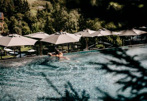 Entspannung und Erholung - Person genießt den Ausblick vom Hotelpool in die Natur